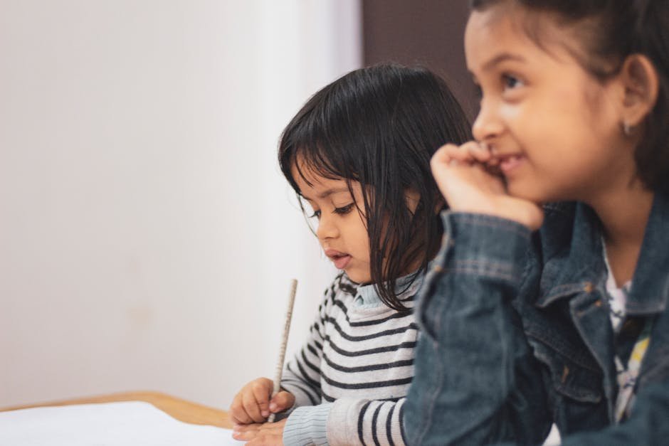 pexels-photo-1720188-1720188 Two young girls joyfully engaged in creative learning indoors, capturing a candid moment of togetherness.